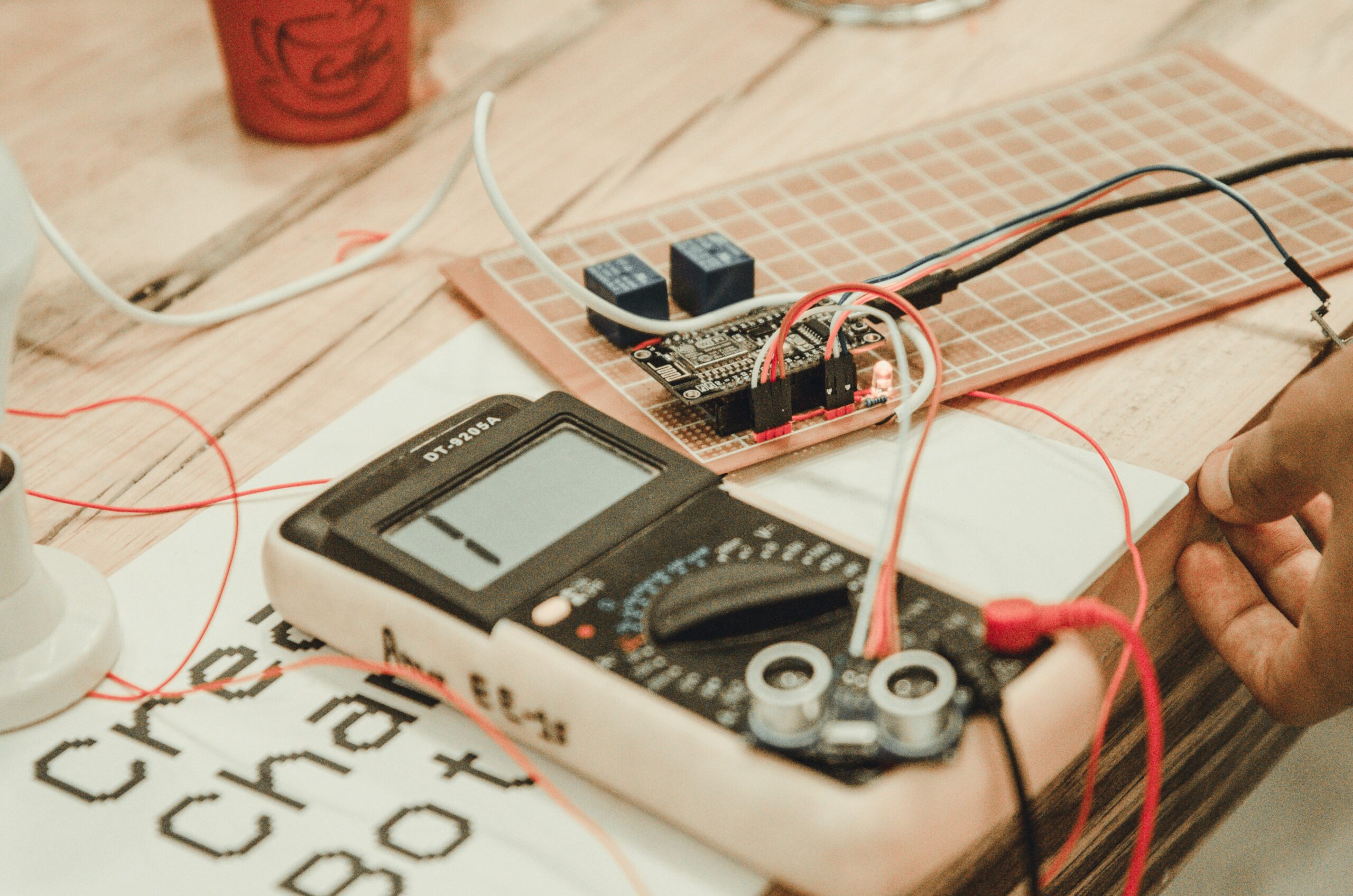 An experienced electrician using a multi-function tester on a three-phase distribution board during a Level 3 Inspection and Testing electrical course.