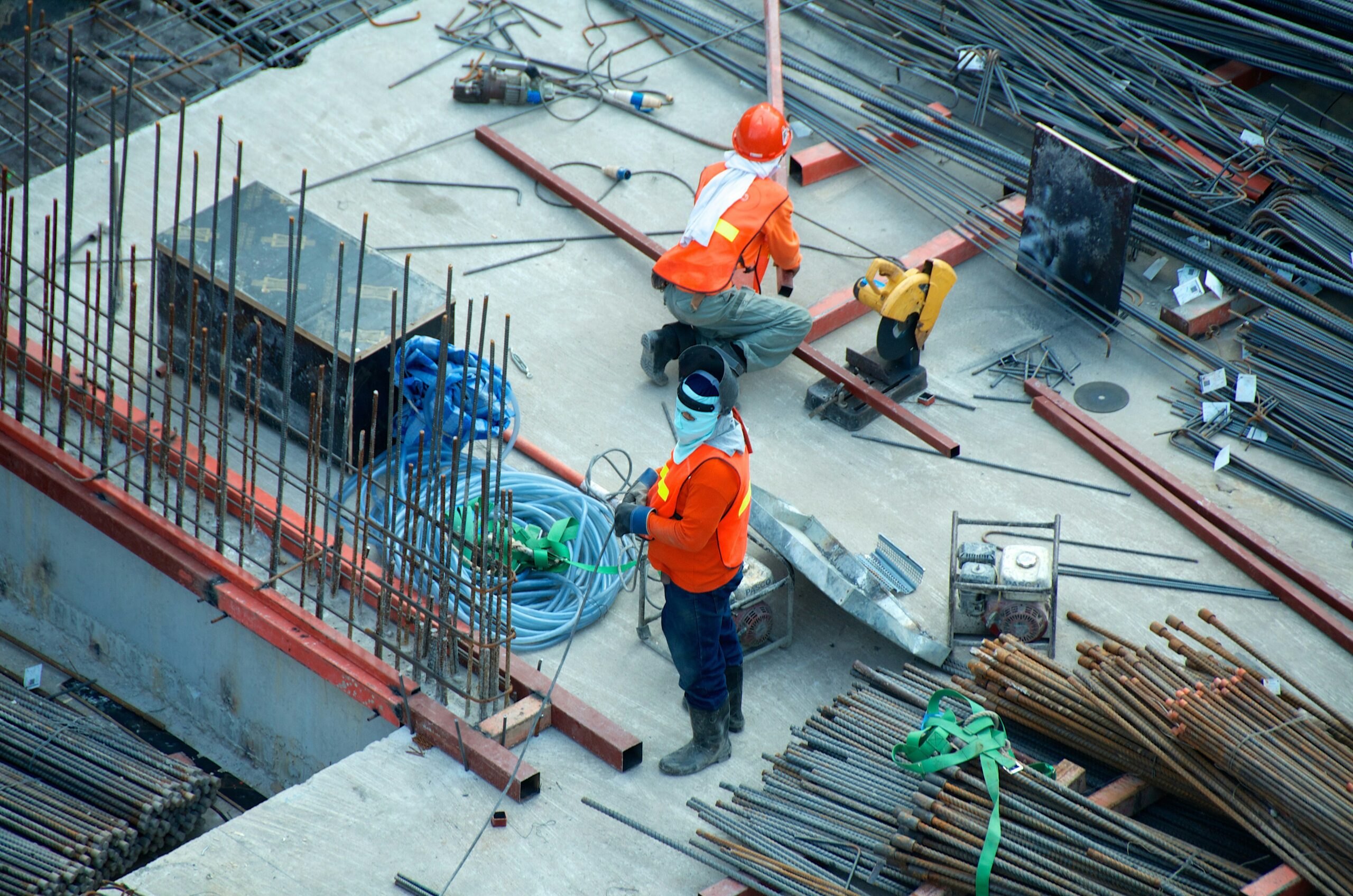 A motivated young worker wearing high-visibility gear and a hard hat smiling on a UK construction site.