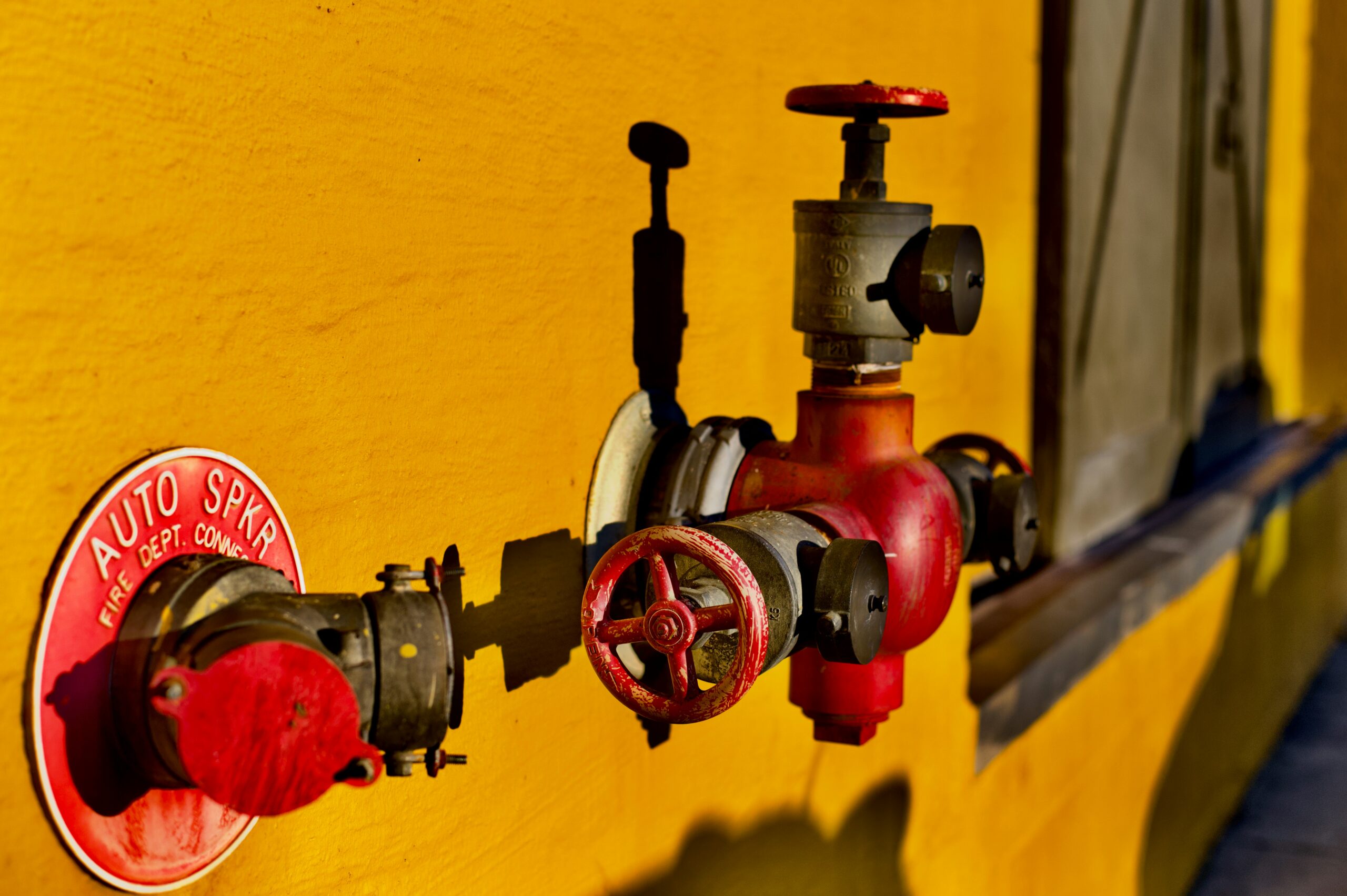 Featured Image Alt Text: A fire safety engineer inspects a commercial fire sprinkler pipework installation in a warehouse ceiling.