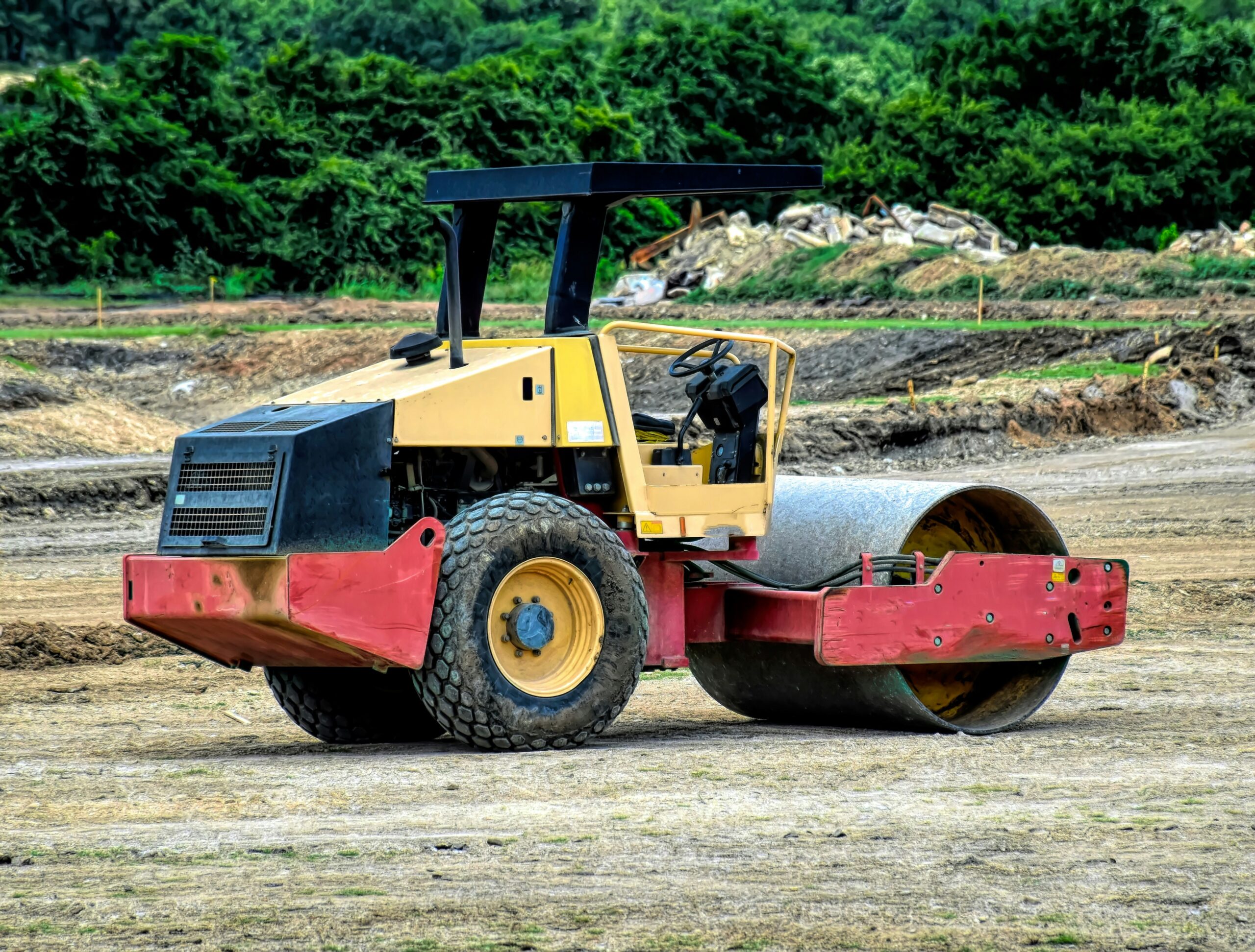 A trainee operating a ride-on roller and a forward tipping dumper truck during a practical plant operator training session on a London construction site.