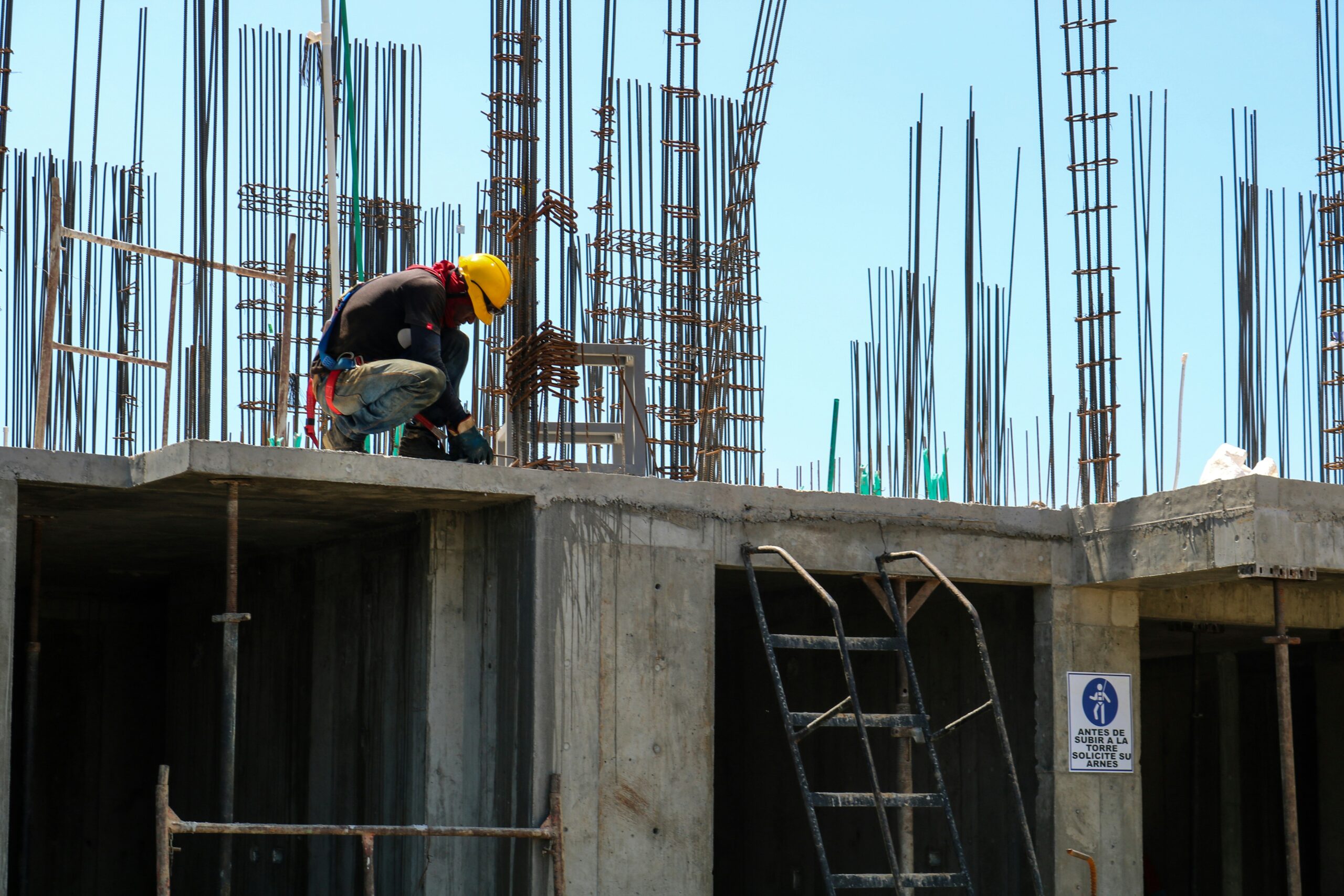 A professional lifting operative guiding a tower crane hook while completing the CPCS NVQ Slinger qualification on site.